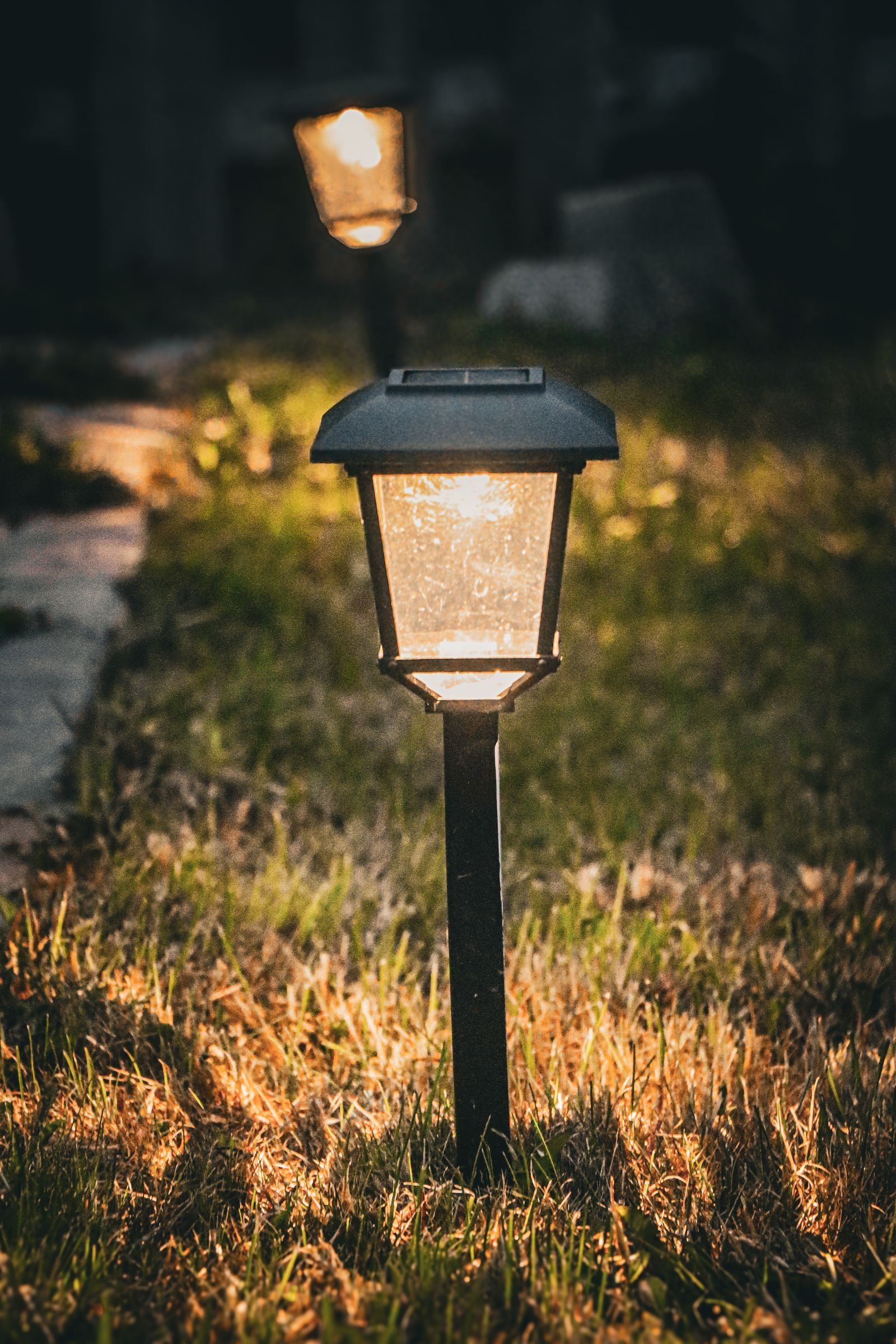 Low garden pathway light glowing warmly along a walkway at dusk