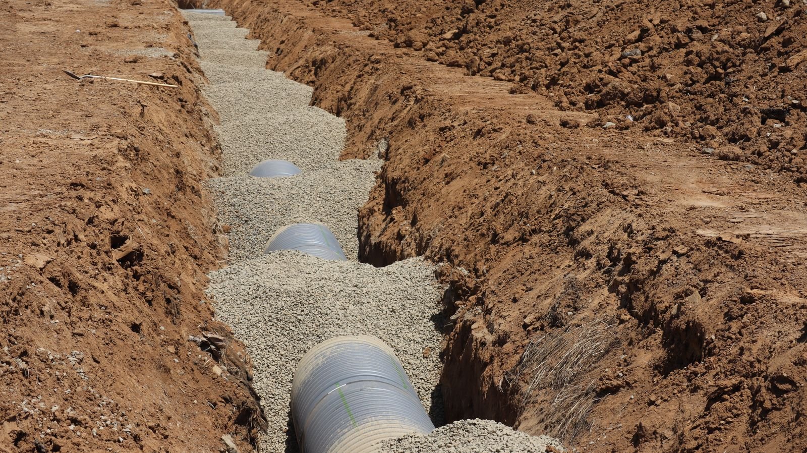 Drainage pipe being installed in a trench dug through a yard