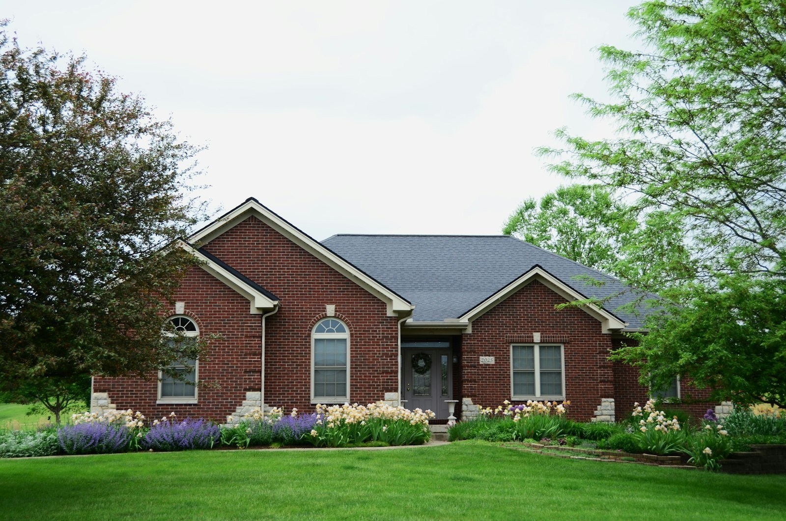 Layered foundation plantings and a flower-lined walkway leading to the front entry of a home