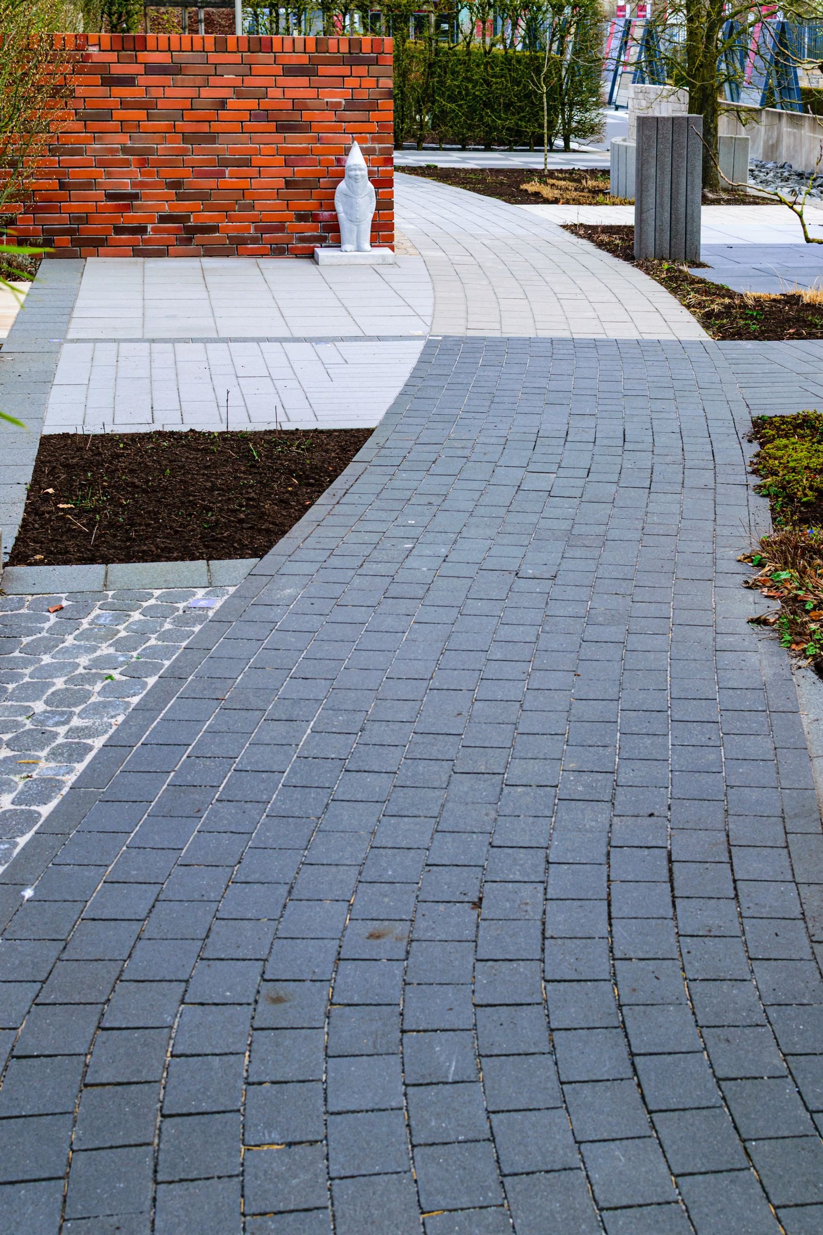 A curved paver walkway running through planting beds